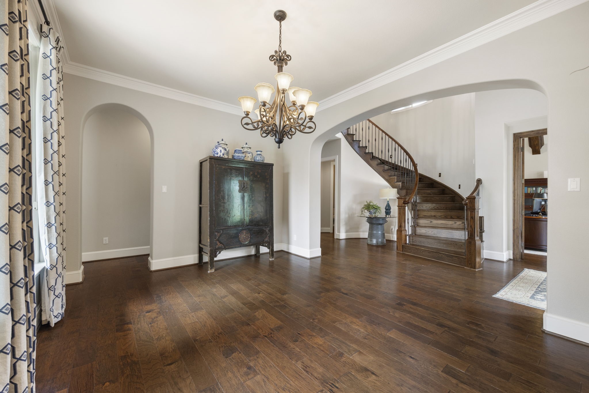 22 Marin Creek Place Spring, TX 77389 - Photo 7 of 38 Formal dining room featuring rich wood flooring, crown molding, and a decorative chandelier. Arched openings and architectural detailing frame a warm and inviting setting for entertaining.