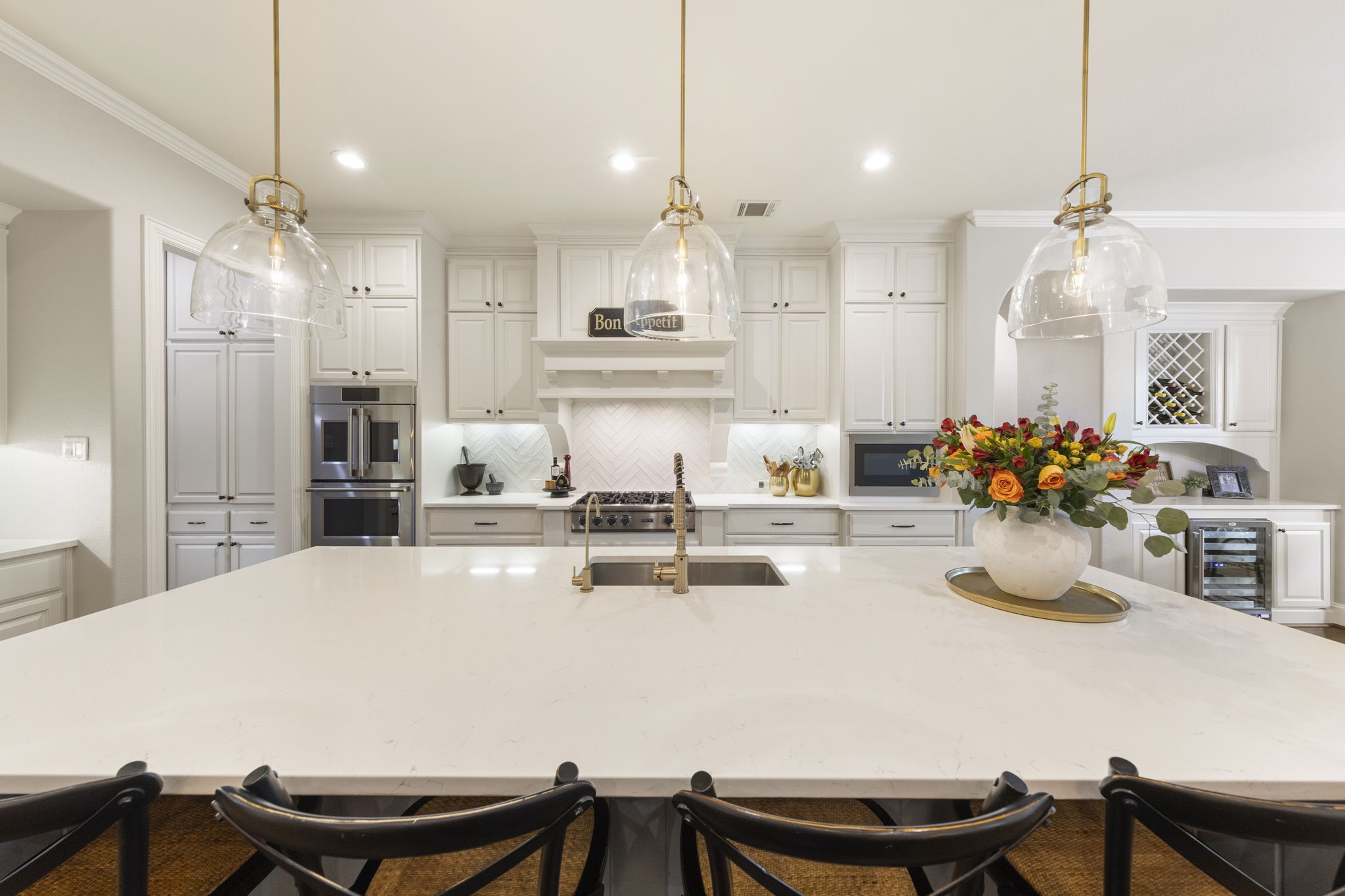 22 Marin Creek Place Spring, TX 77389 - Photo 10 of 38 Chef’s kitchen with an oversized island, quartz countertops, custom cabinetry, and statement glass pendant lighting. High-end appliances and elegant finishes create a sophisticated culinary space.