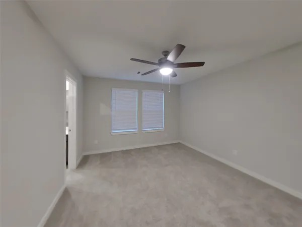 an empty room with a ceiling fan and a window