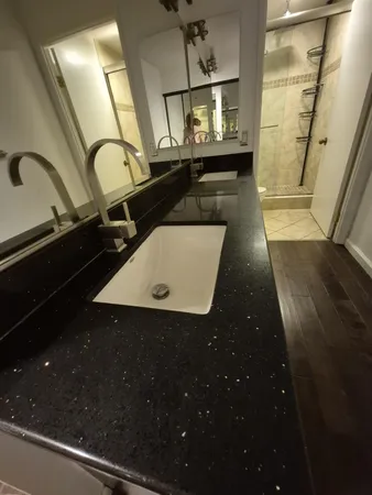 a bathroom with a granite countertop sink toilet a mirror and shower