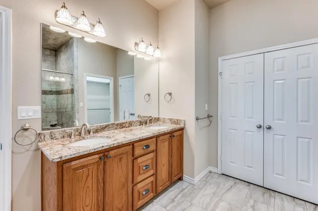 a bathroom with a granite countertop double vanity sink and a mirror