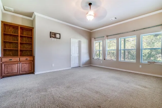 a view of an empty room with a window and cabinet
