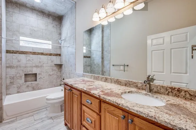 a bathroom with a granite countertop bathtub a sink and a mirror