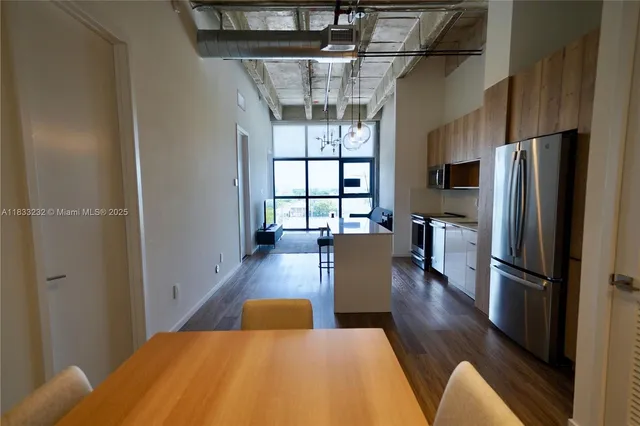 a kitchen with stainless steel appliances a dining table chairs and a refrigerator