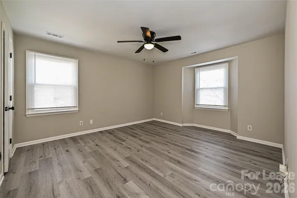 a view of empty room with wooden floor and fan