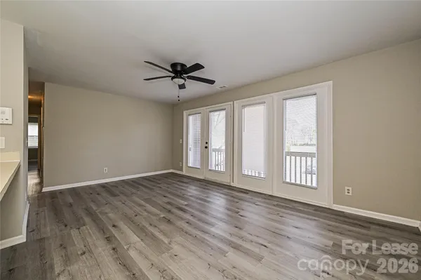 a view of an empty room with a window and wooden floor