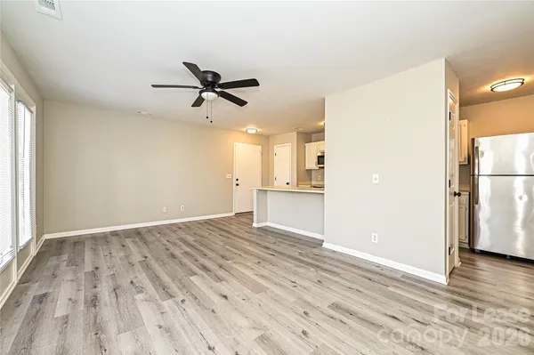 a view of empty room with wooden floor and kitchen view