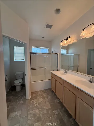 a bathroom with a granite countertop sink mirror and toilet