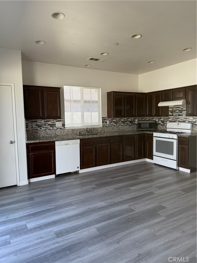 2062 Splendid Circle San Jacinto, CA 92582 - Photo 4 of 18 a large kitchen with a stove top oven a sink and dishwasher a oven with wooden floors