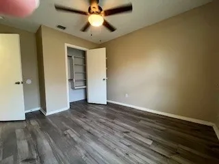 an empty room with wooden floor and a ceiling fan
