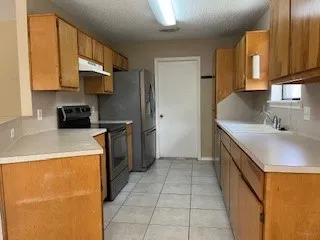 a kitchen with a sink a stove top oven and a refrigerator