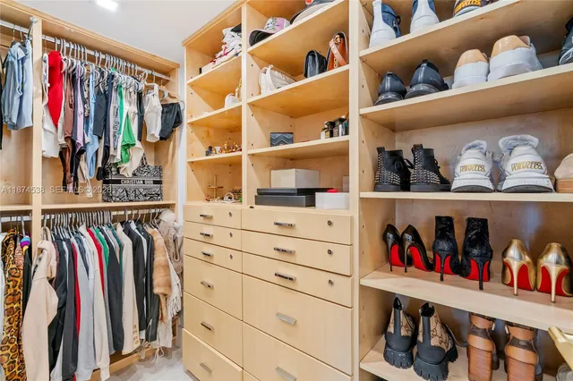 a view of walk in closet with clothes and shoes