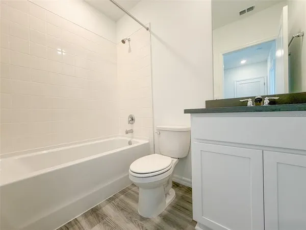 a bathroom with a granite countertop toilet a sink and a mirror