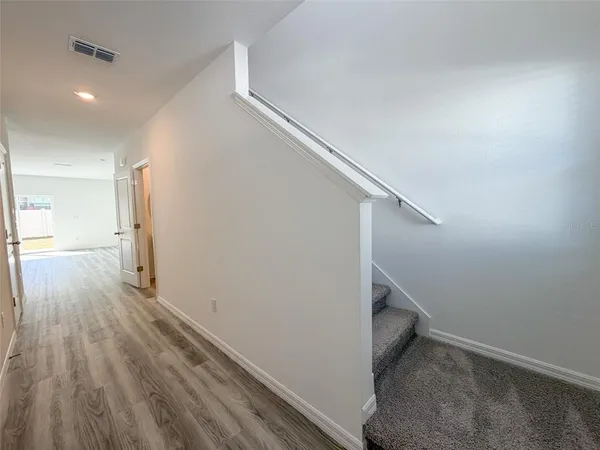 a view of a hallway with wooden floor and stairs