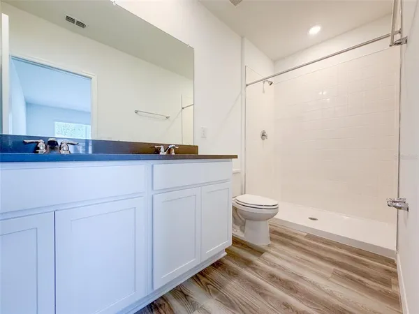 a bathroom with a granite countertop sink toilet a mirror and shower