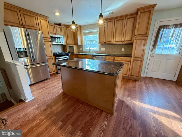 a kitchen with stainless steel appliances granite countertop a refrigerator a stove a sink and a hard wood floors