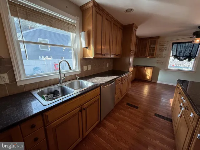 a kitchen with stainless steel appliances granite countertop a sink a stove and a wooden floor