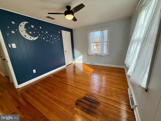 a view of an empty room with window and hardwood floor