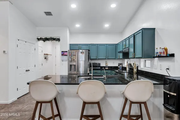 a kitchen with stainless steel appliances a dining table chairs and a refrigerator