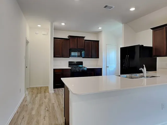 a large kitchen with stainless steel appliances a large counter top a stove and a refrigerator