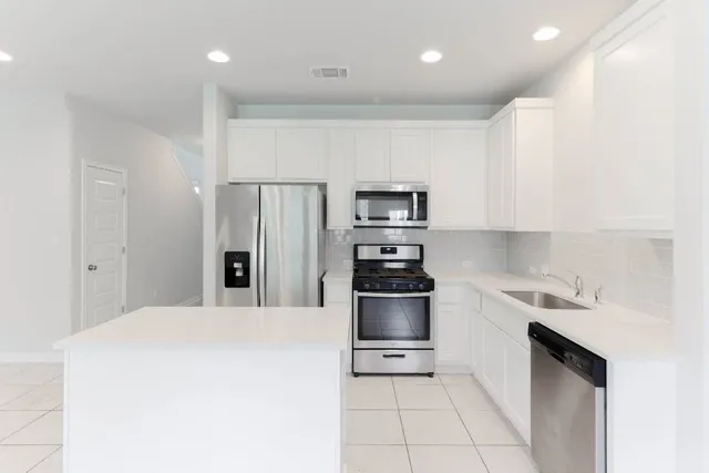 a kitchen with stainless steel appliances a refrigerator sink and microwave