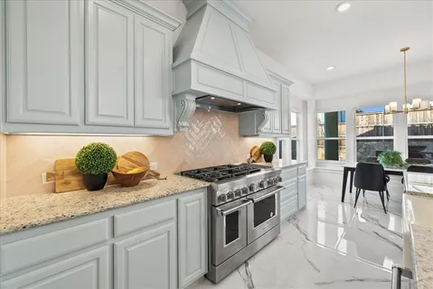 a kitchen with stainless steel appliances granite countertop a stove and a white cabinets