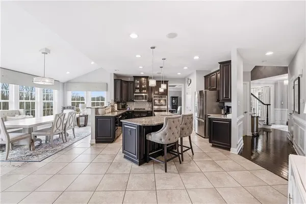 a kitchen with stainless steel appliances kitchen island granite countertop a table chairs and a refrigerator