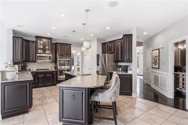 a kitchen with stainless steel appliances granite countertop a stove top oven a sink refrigerator and cabinets