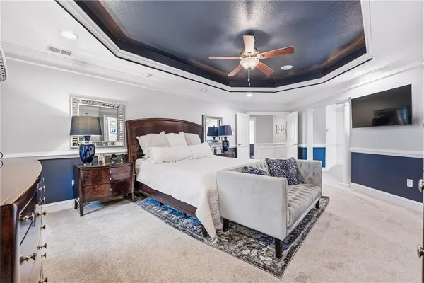 a spacious bedroom with a bed a flat screen tv and a chandelier