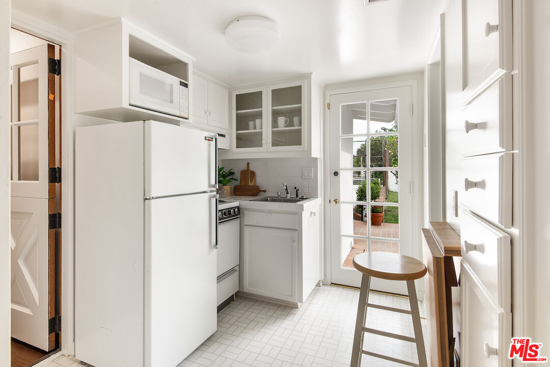 27280 Eastvale Road Palos Verdes Peninsula, CA 90274 - Photo 15 of 34 a kitchen with a refrigerator a stove and white cabinets