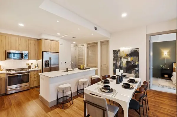 a kitchen with a dining table cabinets appliances and wooden floor