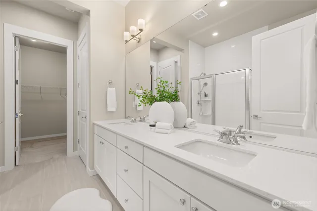 a bathroom with double vanity sinks a vanity a lamp and a mirror