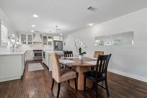 a view of a dining room and livingroom with furniture wooden floor a rug a painting and a chandelier
