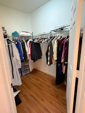 a view of walk in closet with clothes and shoes