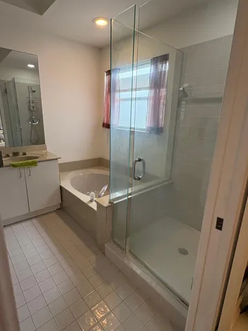a bathroom with a tub a mirror and a shower