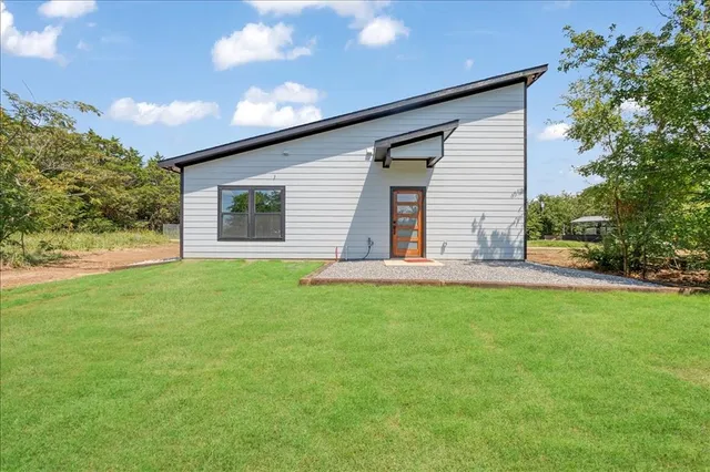 a backyard of a house with plants and large tree