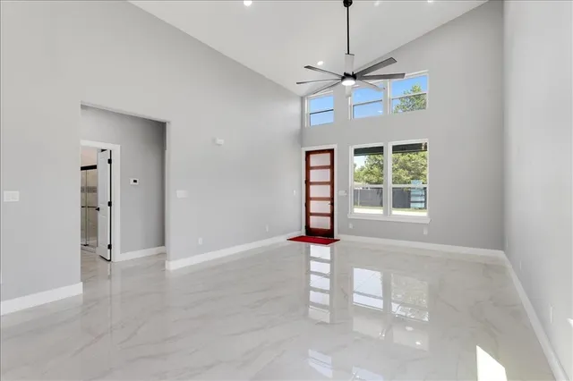 an empty room with windows and ceiling fan