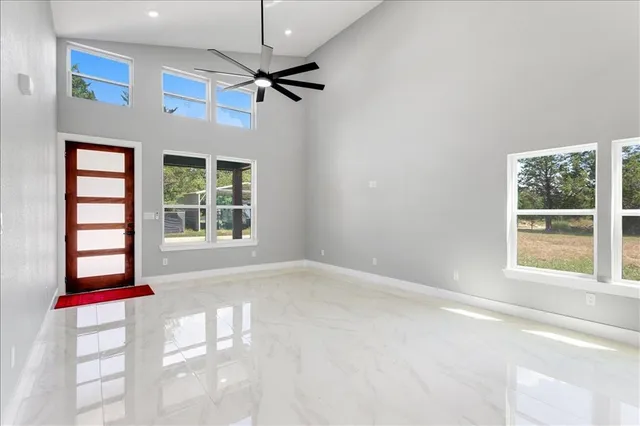 an empty room with windows and ceiling fan