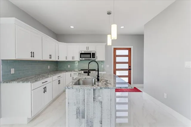 a kitchen with stainless steel appliances granite countertop a sink stove oven and white cabinets