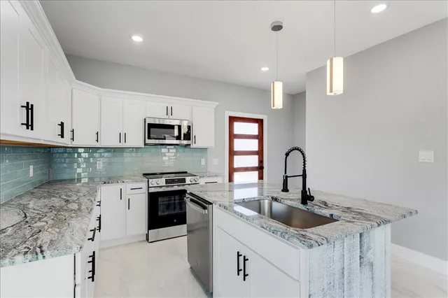 a view of a kitchen with kitchen island stainless steel appliances refrigerator sink and cabinets