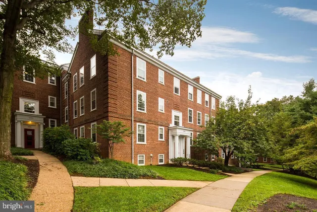 a view of a building next to a big yard and large trees