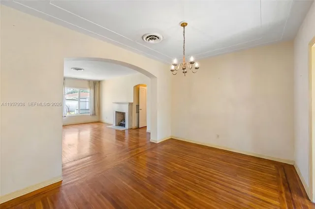 a view of an empty room with window and wooden floor