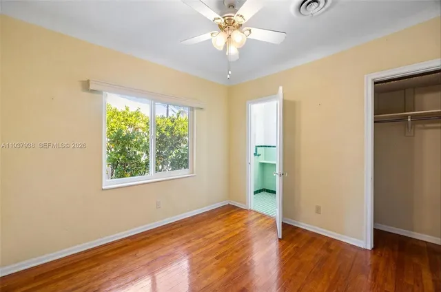a view of an empty room with window and wooden floor