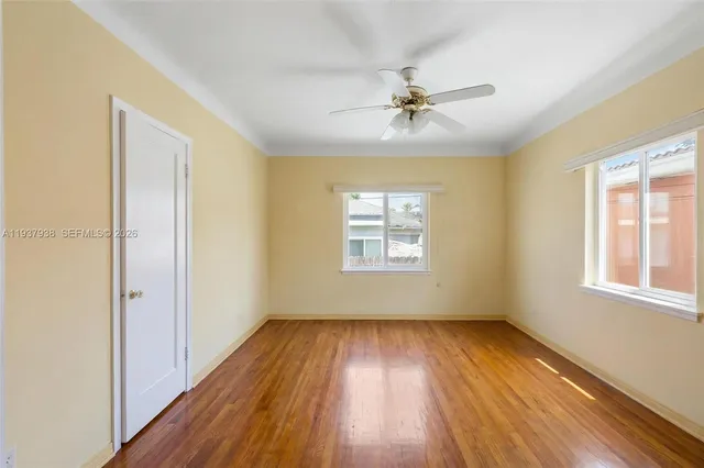 a view of empty room with wooden floor and fan
