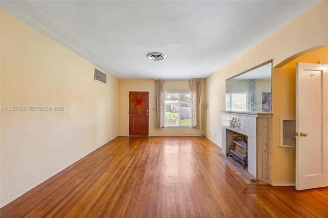 a view of an empty room with window and wooden floor