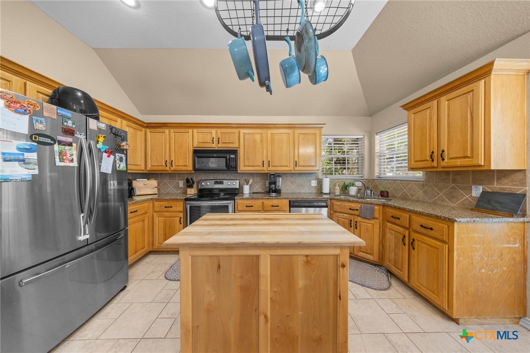 108 Gehler Circle Nolanville, TX 76559 - Photo 11 of 27 a kitchen with stainless steel appliances granite countertop a refrigerator a sink dishwasher a stove and a dining table with wooden floor