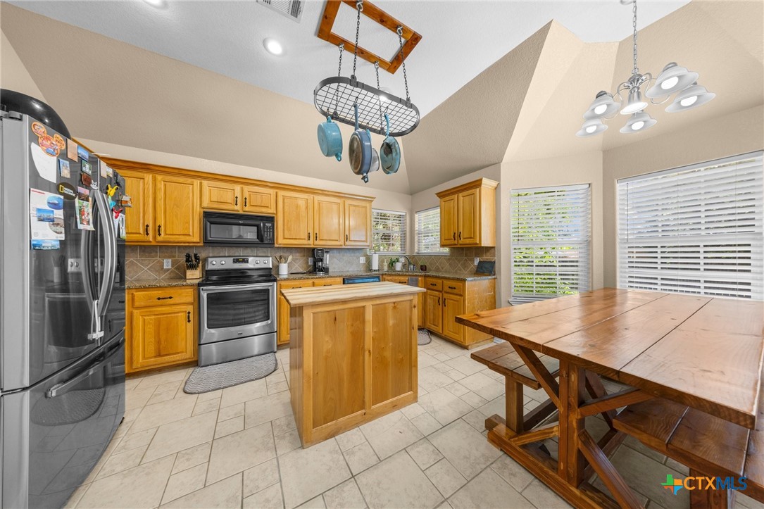108 Gehler Circle Nolanville, TX 76559 - Photo 10 of 27 a kitchen with stainless steel appliances kitchen island granite countertop a refrigerator a stove a sink dishwasher a dining table and chairs with wooden floor