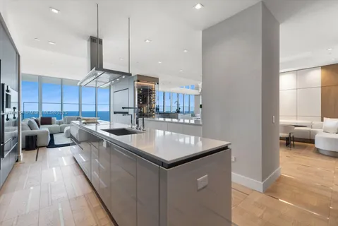 a large kitchen with kitchen island a stove a sink a refrigerator and a dining table with wooden floor