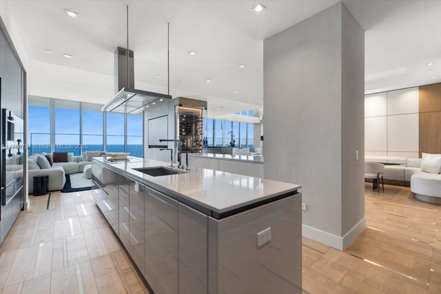 a large kitchen with kitchen island a stove a sink a refrigerator and a dining table with wooden floor