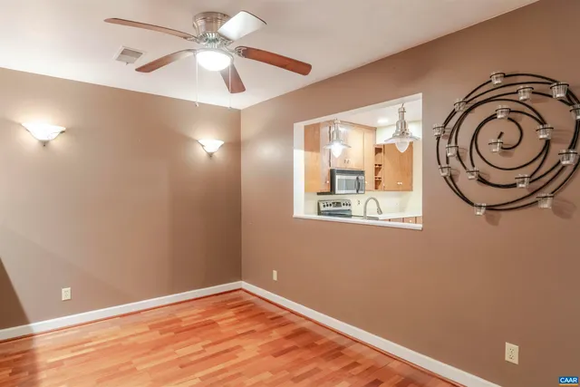 a view of empty room with wooden floor and fan